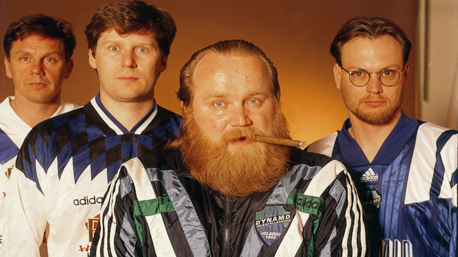Leevi and the Leavings -yhtyeen jäsenet 1990-luvun promokuvassa Adidas-verryttelyasuissa, keskellä Gösta Sundqvist sikari suussa.